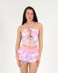 Woman wearing a pink and purple camouflage rave outfit with a white background