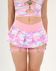 Person wearing a pink and pastel camouflage rave outfit with a matching skirt and garter belt.