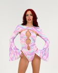 Woman wearing a colorful, patterned rave outfit with long sleeves on a plain background