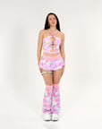 Person wearing a pink and white camouflage rave outfit with matching boots on a white background