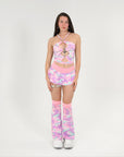 Person wearing a pink and purple camouflage rave outfit with matching socks on a white background