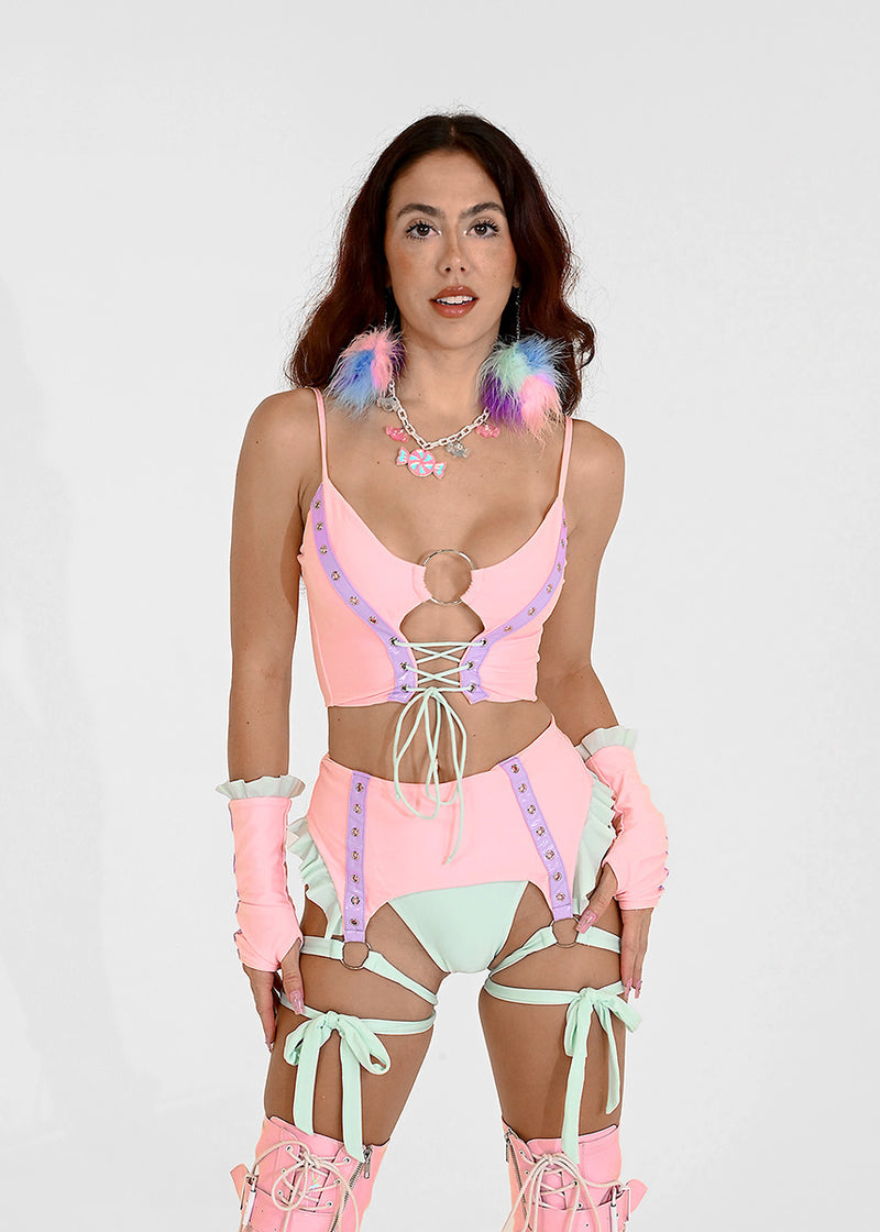 Woman wearing pastel rave matching set outfit with garter belt and crop top.