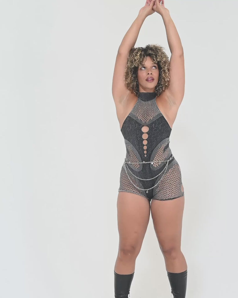 Model wearing a sleeveless mesh jumpsuit with cutout details, shown in a studio environment to demonstrate fit through the torso, waist, and legs during natural movement.