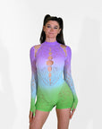 Woman wearing a purple, blue, and green gradient rave outfit with long sleeves and shorts on a white background.