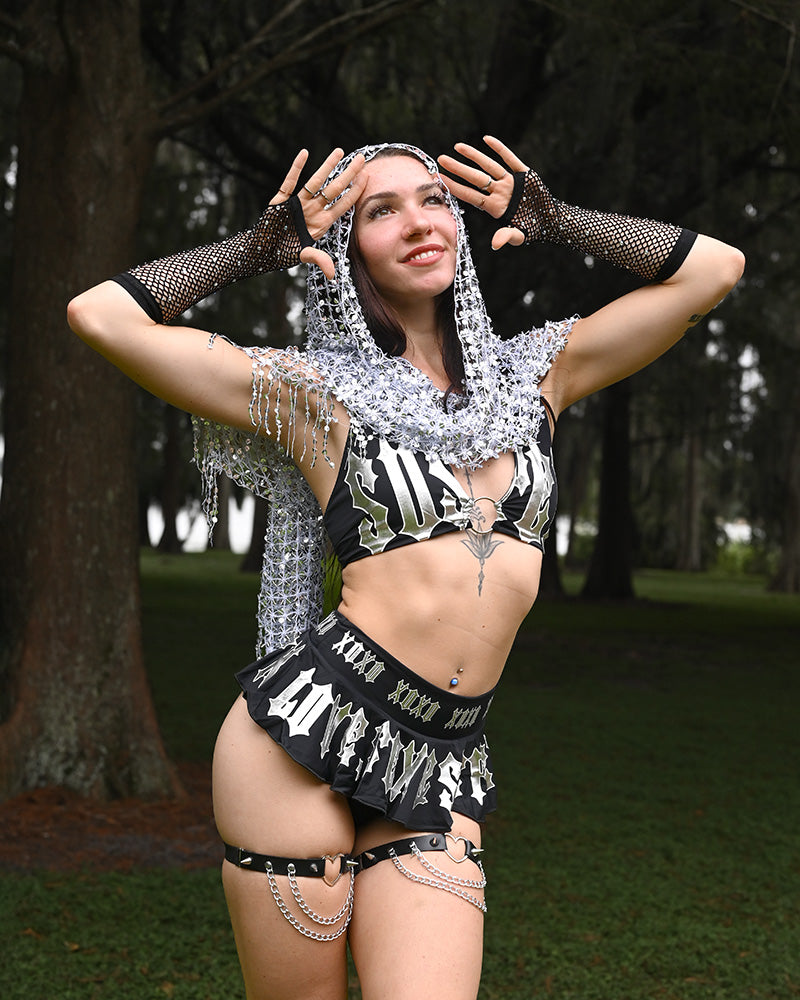 Person in a black and white rave outfit with chains outdoors